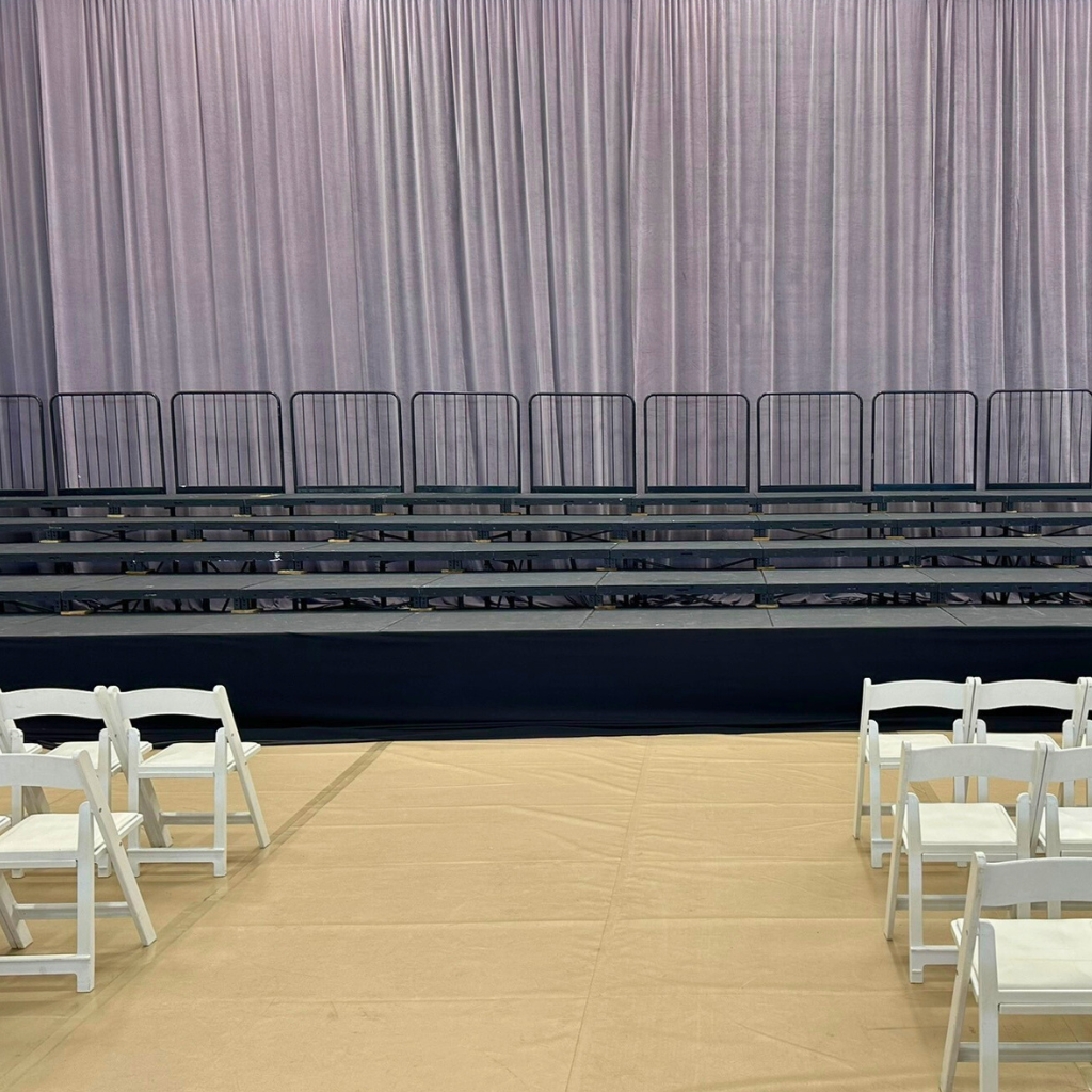 Indoor graduation event setup with stage and audience seating by TLC Event Rentals