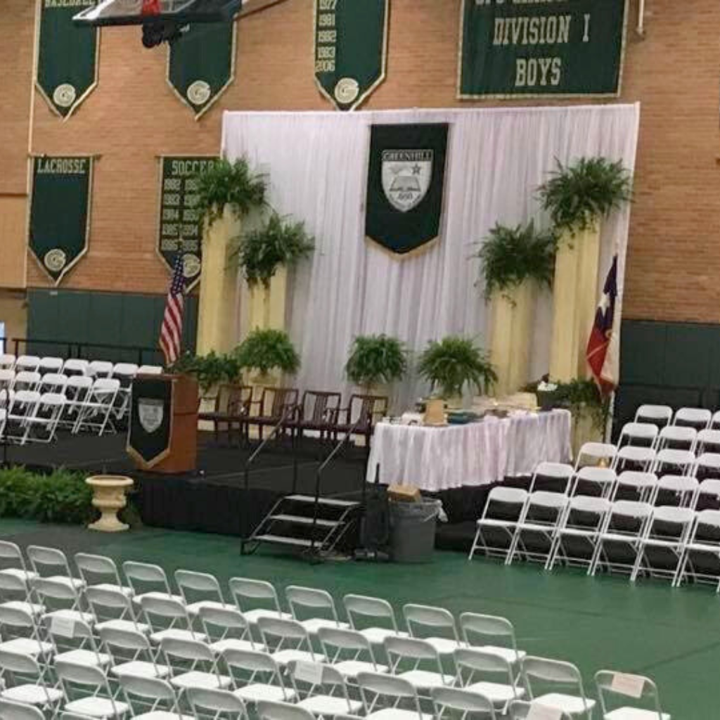 Indoor graduation ceremony setup with stage, podium, seating, and diploma table by TLC Event Rentals