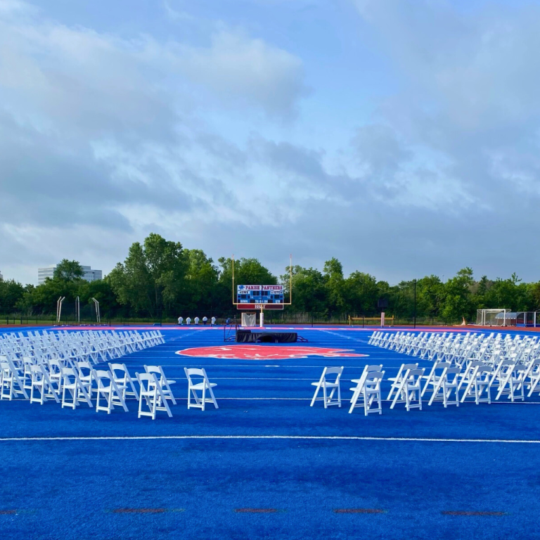 Indoor graduation stage with arranged guest seating by TLC Event Rentals